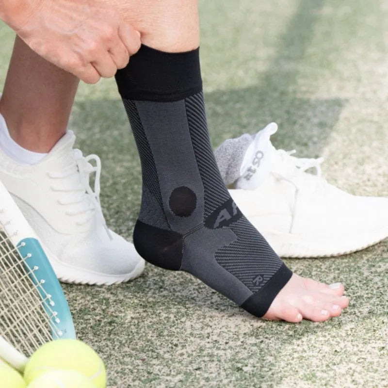 Person putting on the OrthoSleeve Compression Ankle Brace before playing tennis