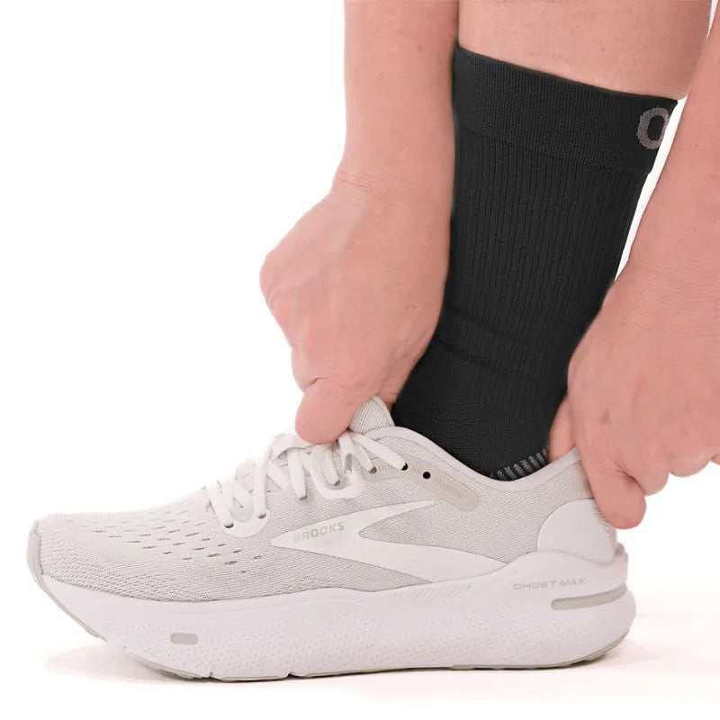 Lifestyle image of someone wearing the black crew length plantar fasciitis socks with shoes on