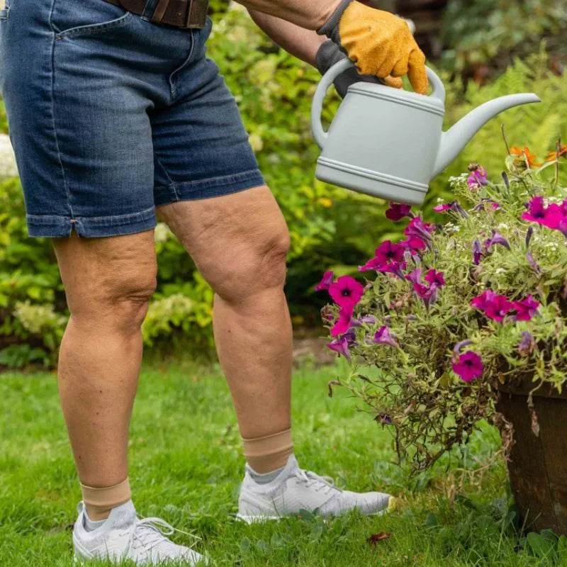 Woman wearing the OrthoSleeve tan Plantar Fasciitis Foot Sleeves while watering the flowers