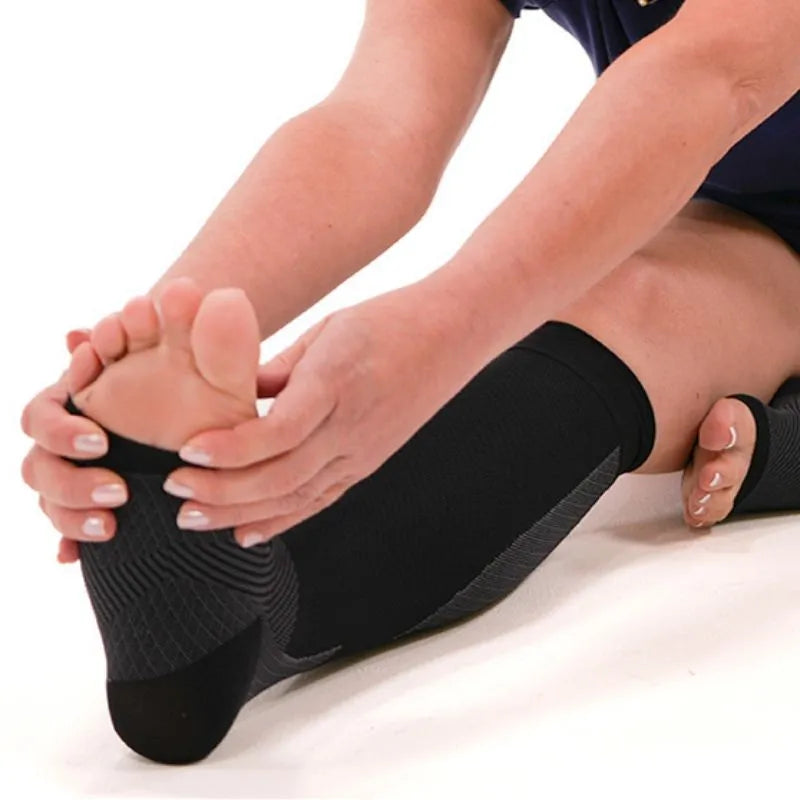 Person shown stretching while wearing the black OrthoSleeve Compression Leg Sleeves