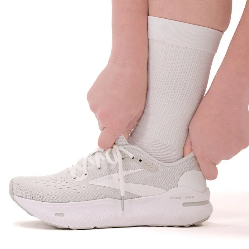 Lifestyle image of someone wearing the OrthoSleeve white crew length plantar fasciitis socks while wearing shoes